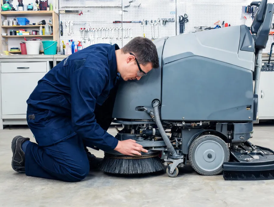 Maintenance technician checking floor scrubber wear items
